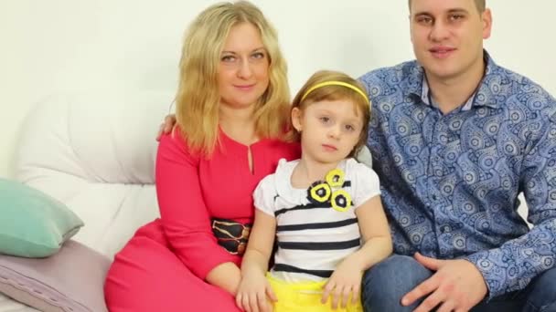 Семья из трех человек сидит на диване — стоковое видео