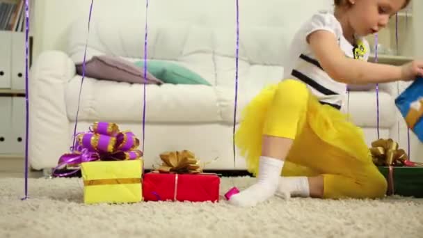 Маленька дівчинка сидить з подарунковими коробками — стокове відео