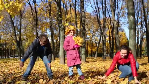 Mutter und Kinder werfen umgestürztes Laub — Stockvideo