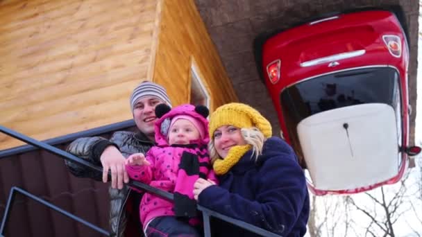 Familie tegen omgekeerde huis met auto — Stockvideo