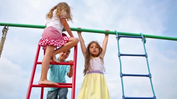 Drei fröhliche Kinder an Spielgeräten. — Stockvideo