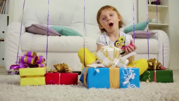 Маленькая девочка сидит с подарочными коробками — стоковое видео