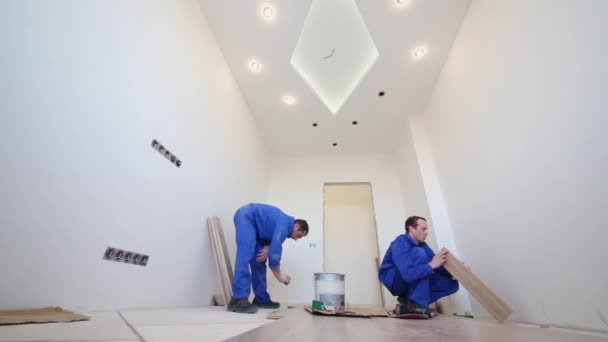 Двоє робітників працюють з паркетними підлогами — стокове відео