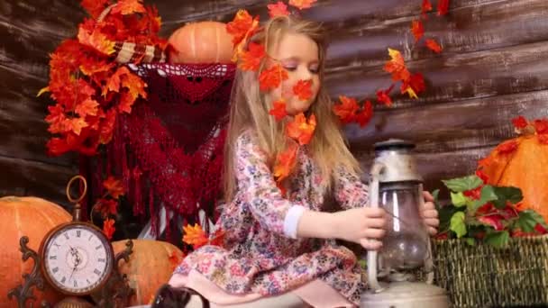 Маленькая девочка сидит в комнате с тыквами — стоковое видео