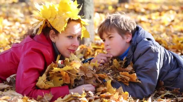 Mère et fils reposent sur des feuilles jaunes — Video