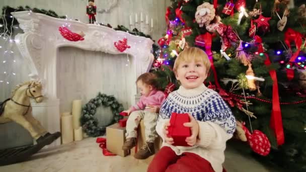 Niña y niño cerca del árbol de Navidad — Vídeos de Stock