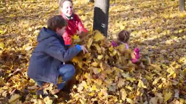 Mother and children throw fallen leaves — Stock Video