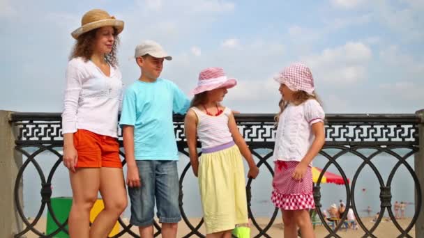 Woman with children standing at railing on embankment. — Stock Video