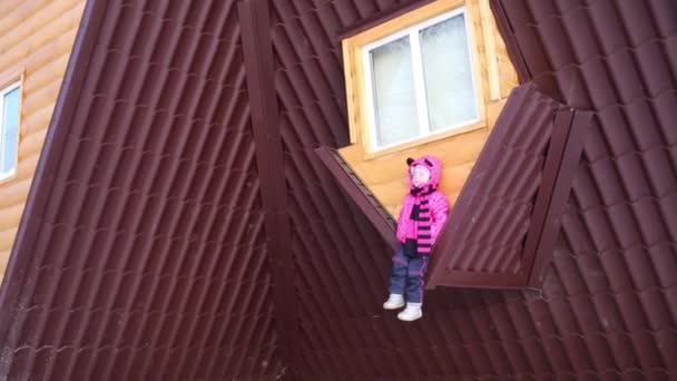 Mała dziewczynka siedzi na brązowy dach odwrócony dom w zimowy dzień — Wideo stockowe