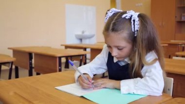 Kız üniformalı okul masa başında oturur 