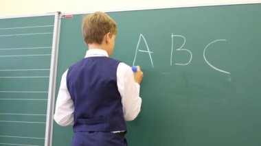 Kara tahta sınıfta yakınındaki çocuk duruyor 