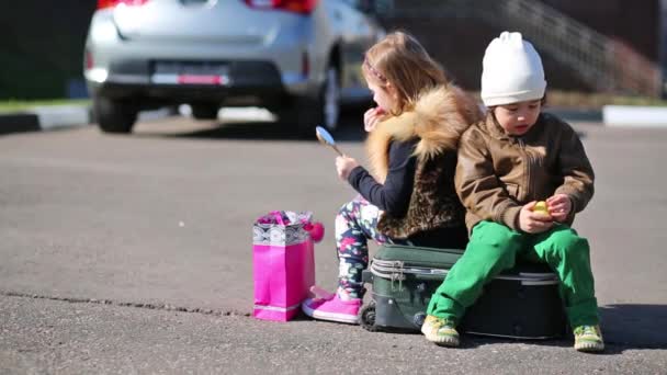 Маленькие дети сидят на чемодане — стоковое видео