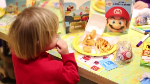 Niño en rojo come en McDonalds — Vídeos de Stock