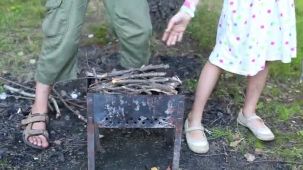 Kohlenbecken und Kinderhände, die Zweige legen — Stockvideo