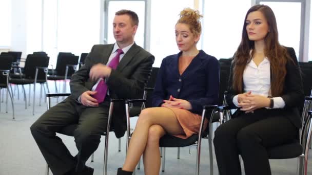 Vrouwen en man zitten op stoelen in de kamer. — Stockvideo