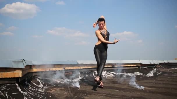 Linda chica baila en el techo con humo en el fondo del cielo azul — Vídeos de Stock