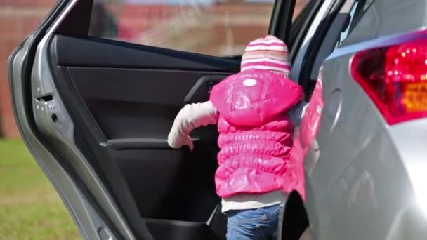 Маленькая девочка сидит у машины — стоковое видео