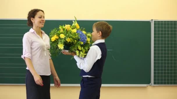 Chłopiec przedstawia kwiaty do nauczyciela w klasie — Wideo stockowe