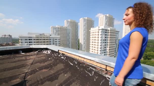 Achterkant van vrouw in blauwe gaande van dak — Stockvideo