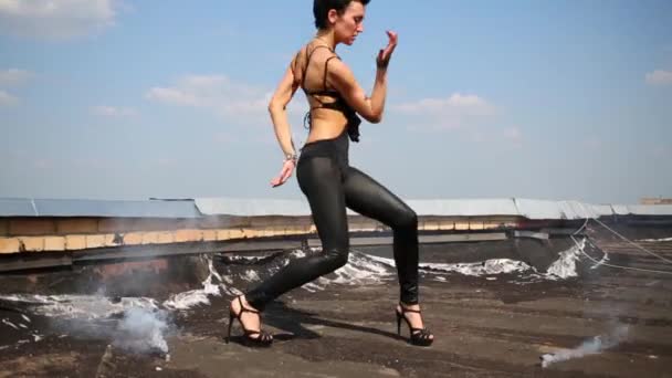 Girl dances on roof with smoke at background of blue sky — Stock Video