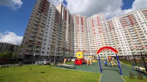 Parque infantil cerca de edificios residenciales altos en el día soleado — Vídeos de Stock