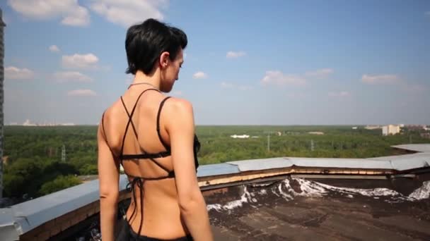 Rücken einer Frau in schwarzem Kostüm, die auf Dach geht — Stockvideo