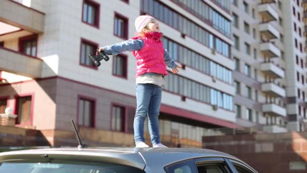 Mała dziewczynka, stojąc na dachu samochodu — Wideo stockowe