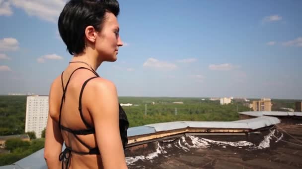 Achterkant vrouw lopen op dak bij achtergrond van gebouwen — Stockvideo