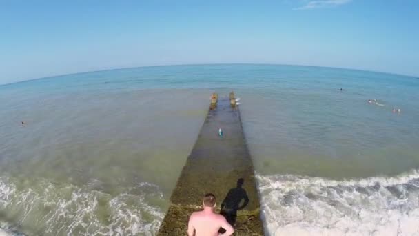 Pareja caminando por el páramo de piedra en el mar — Vídeo de stock