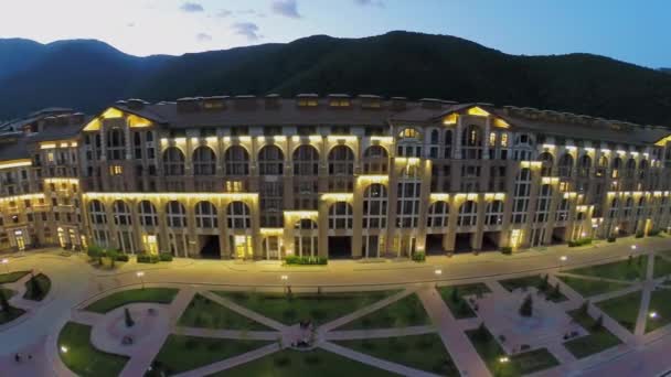 Edificio iluminado de hotel cerca de montañas — Vídeos de Stock