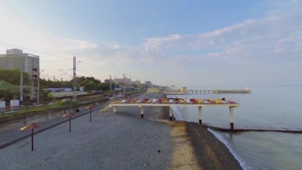 Ferrocarril cerca de la playa de guijarros con sombrillas — Vídeo de stock