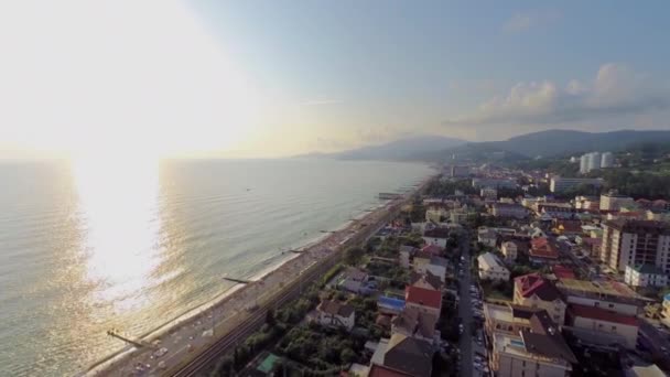 Paisaje marino con sol en el horizonte y gente en la playa — Vídeo de stock