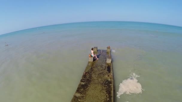 Woman in swimsuit sits on moorage — Stock Video