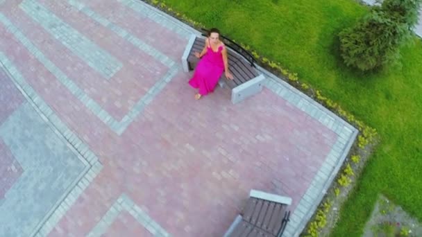 Woman in pink dress sits on bench — Stock Video