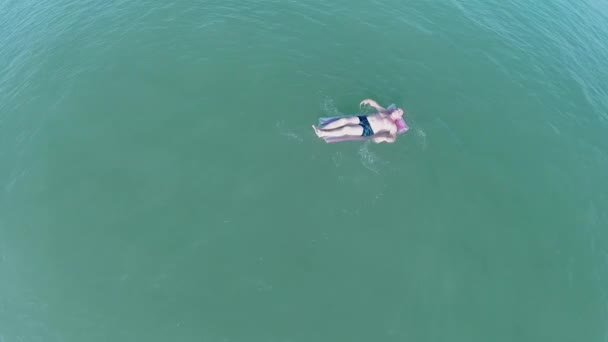 Пенсионер плавает на надувном матрасе — стоковое видео