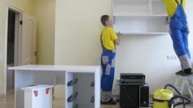 İki işçi raf asmak hazırlanıyor.