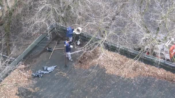Двома працівники знімають листя з даху — стокове відео