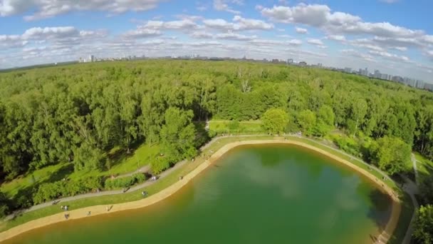 Пруд в парке "Сокольники" с городским пейзажем — стоковое видео