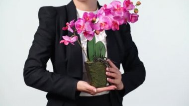 Orkide tutan takım elbiseli kadın