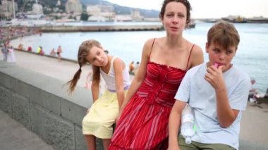 Anne ve çocuk oturur ve deniz dolgu üzerinde görüşmeler 