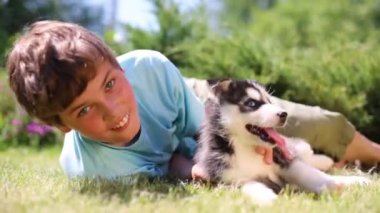 Çocuk köpek yavrusu husky ile çim üzerinde yatıyor 
