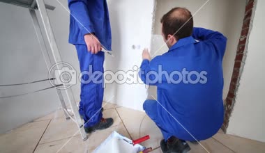 İşçiler bir parça fiberglas kapının yakınındaki duvara tutkallar