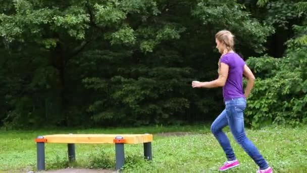 Девушка запрыгивает на скамейку — стоковое видео