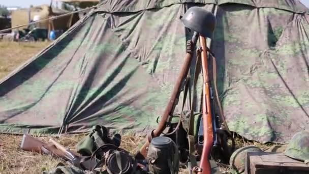Arma e equipamento militar empilhados ao lado da tenda — Vídeo de Stock
