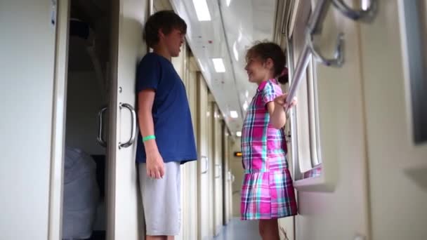 Junge und Mädchen im Korridor eines fahrenden Zuges — Stockvideo