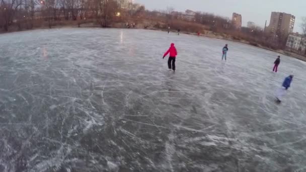 Дети катаются и играют на ледяном пруду — стоковое видео