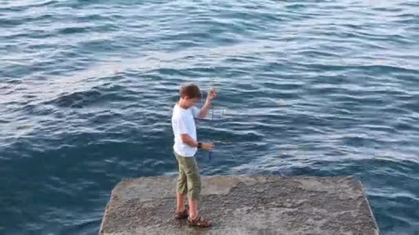 Boy with rod fishing in sea — Stock Video