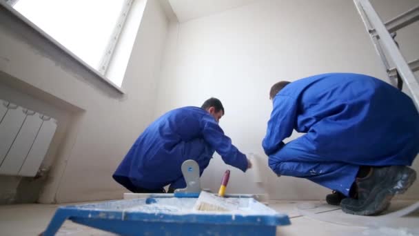 Робочі приклеюють склопластиковий лист до стіни, згладжуючи його валиком — стокове відео