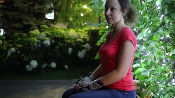 Mujer se sienta en el banco en el jardín — Vídeo de stock
