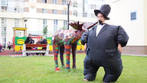 Chica en traje inflable cerca de la escultura de alce — Vídeos de Stock